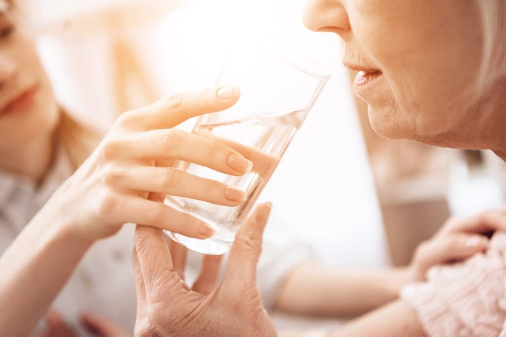 woman in long term care being given water